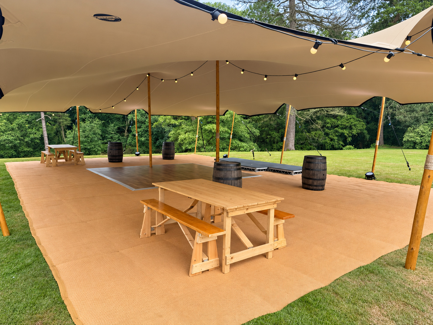 Festoon lighting and a dance floor inside a stretch tent