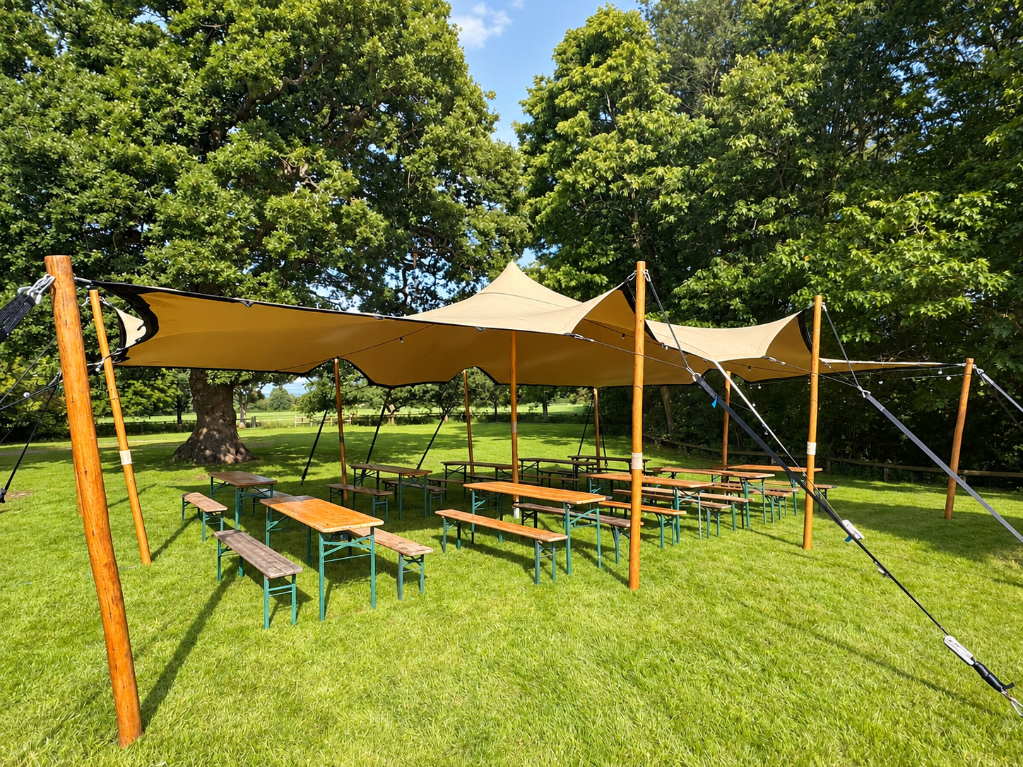 Stretch tent shading picnic tables on a tree-lined lawn